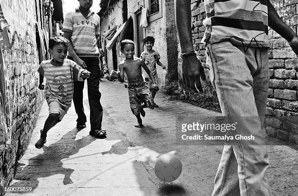 Three street children are playing football on the narrow lanes of north Calcutta. They are happily enjoying the game.