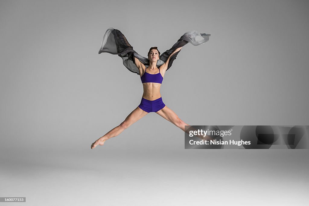 Ballerina in the air wile holding silk