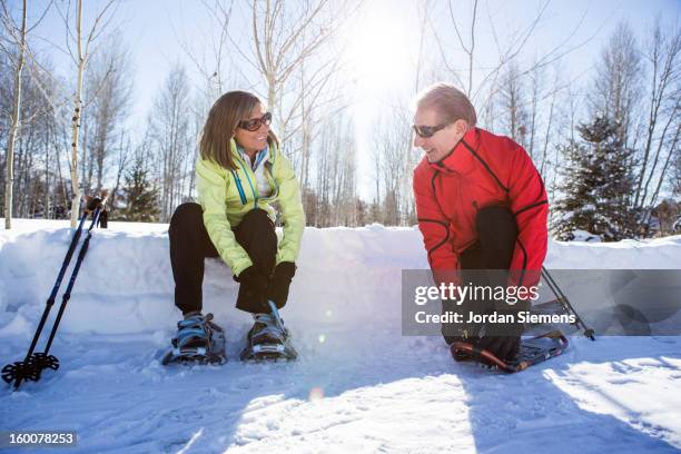 older couple snowshoeing in the winter. - snowshoe stock pictures, royalty-free photos & images