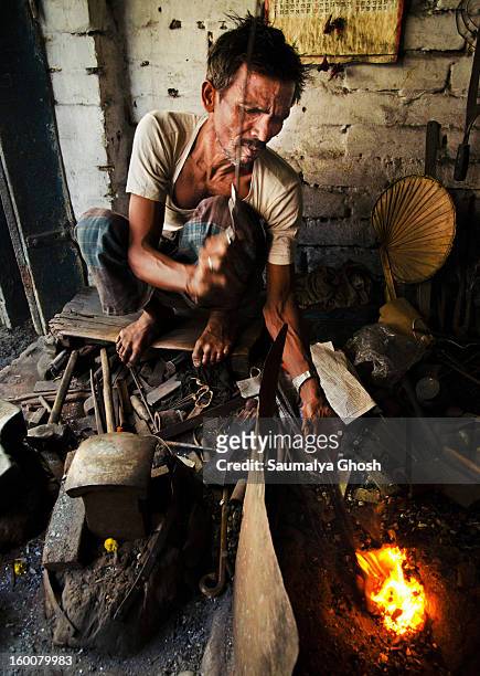 Metal-worker is heating an iron bar at his workplace in Kolkata.