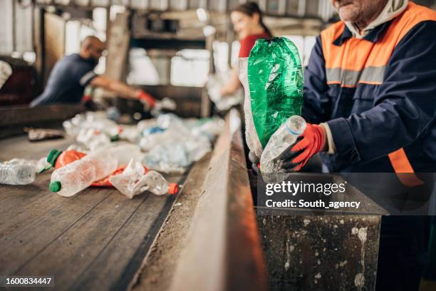 group of workers at the recycling centre sorting plastic waste ad preparing for recycling - recycling center stock pictures, royalty-free photos & images