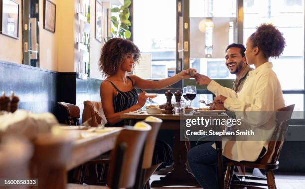 group of friends having dinner together in fashionable restaurant cafe - friends dinner stock pictures, royalty-free photos & images