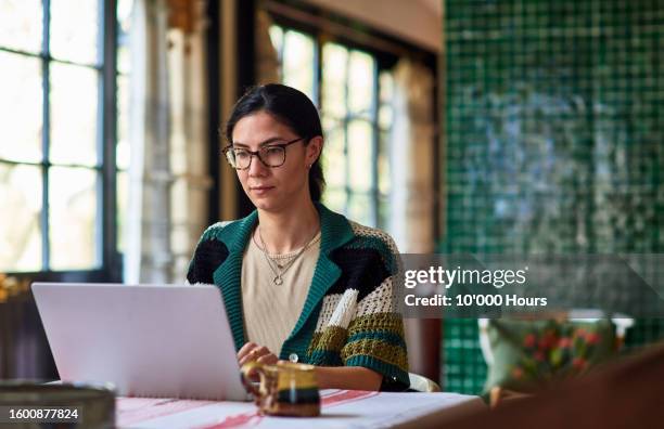 multiracial woman using laptop in home office - usar el ordenador fotografías e imágenes de stock