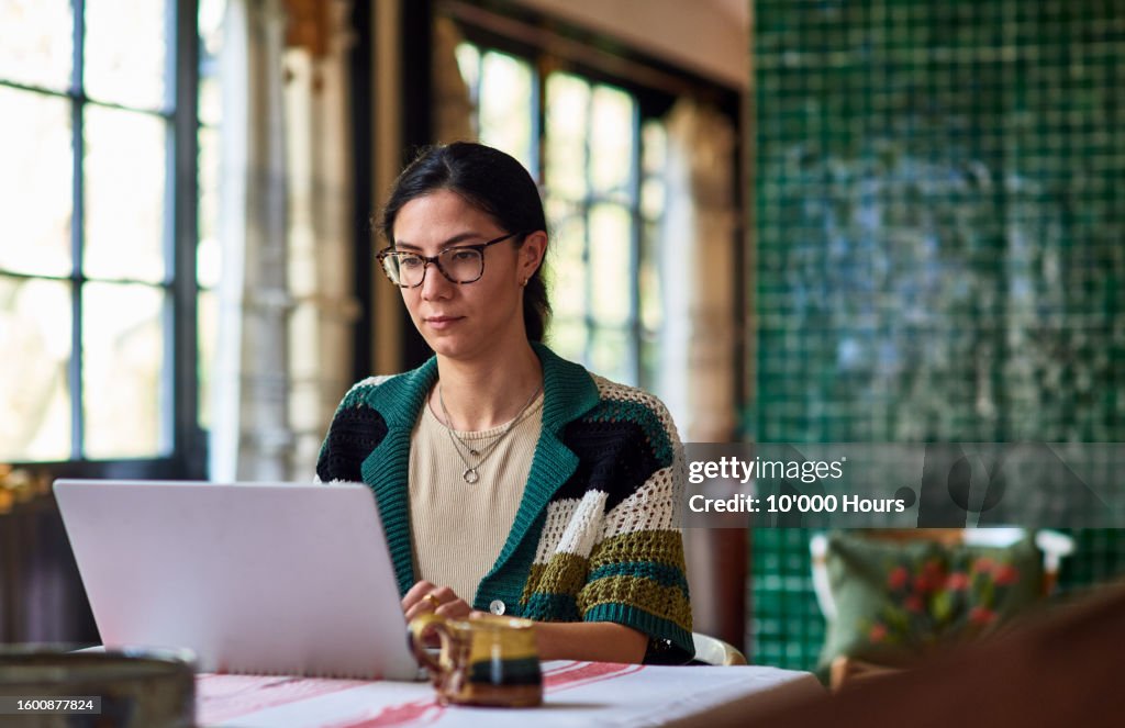 Multiracial woman using laptop in home office