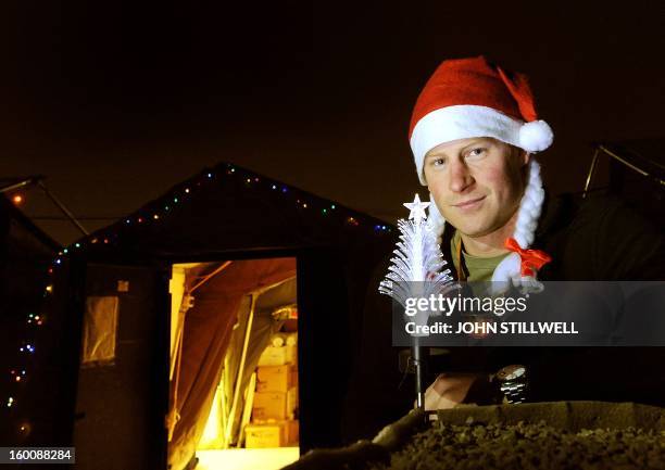 This picture taken on December 12, 2012 shows Britain's Prince Harry wearing a Christmas Hat as he stands outside the VHR tent at Camp Bastion in...