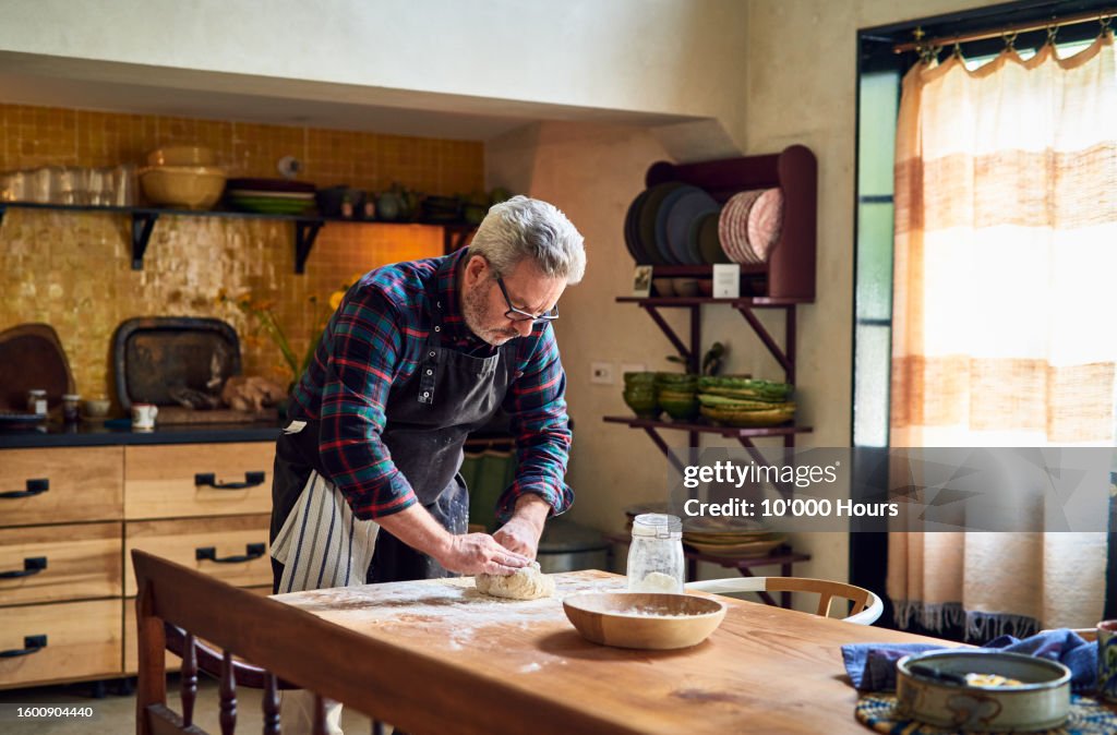 Senior man making bread in kitchen