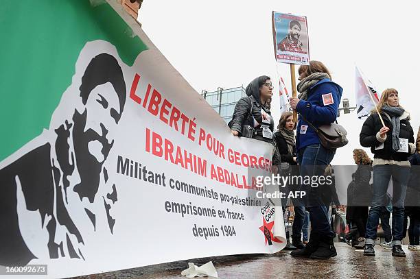 People hold a banner with a portrait of Georges Ibrahim Abdallah, a pro-palestinian militant, and reading "Freedom for Georges Ibrahim Abdallh"...