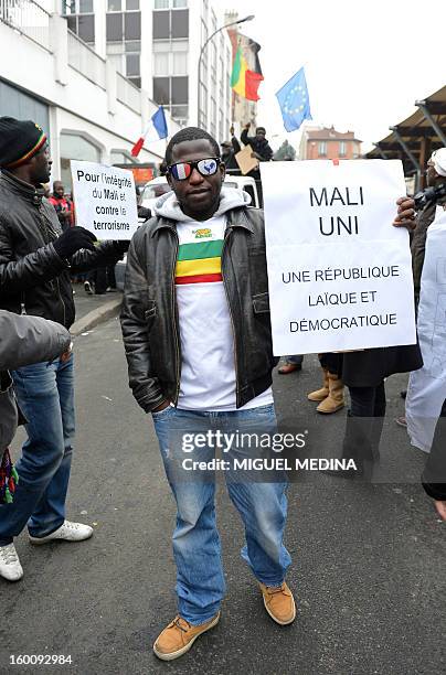 Man, waring glasses with painted French flag and French rooster symbol, holds a placard reading "United Mali : a laic and democratic republic" during...