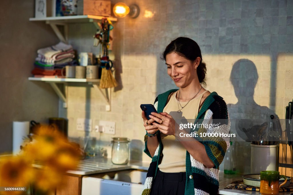 Smiling mid adult woman using social media on smart phone