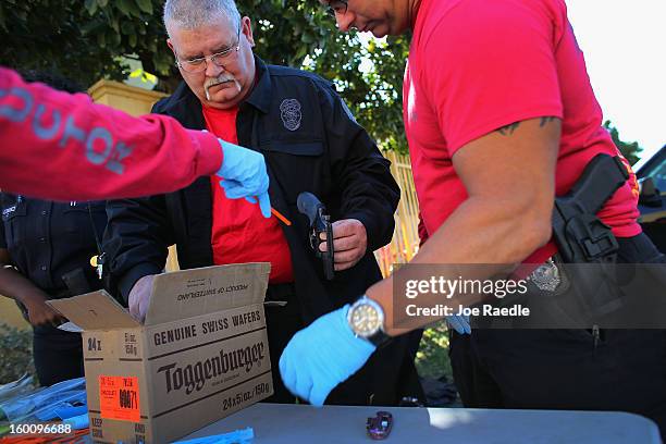 City of Miami police officer Robert Novo along with other police officers take in weapons during a gun buy back event on January 26, 2013 in Miami,...