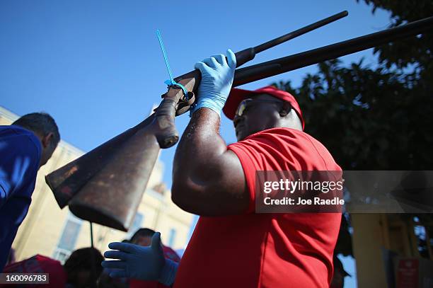 City of Miami police officers Walter Byars holds two weapons as he processes them during a gun buy back event on January 26, 2013 in Miami, Florida....