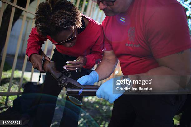 City of Miami police officers Latrice Payen and Luis Gonzalez process a shotgun that was turned in during a gun buy back event on January 26, 2013 in...