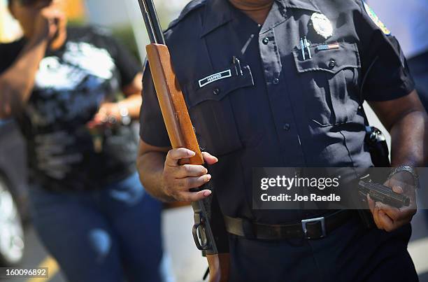 City of Miami police officers Kelvin Harris carries a handgun and rife that were turned in during a gun buy back event on January 26, 2013 in Miami,...