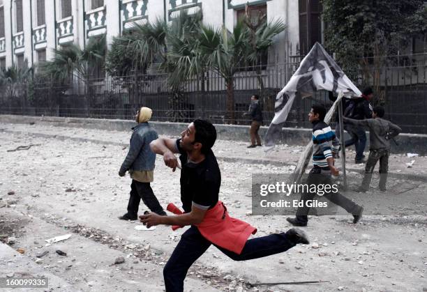 An Egyptian protester throws a rock toward Egyptian riot police during a protest following the announcement of the death penalty for 21 suspects in...