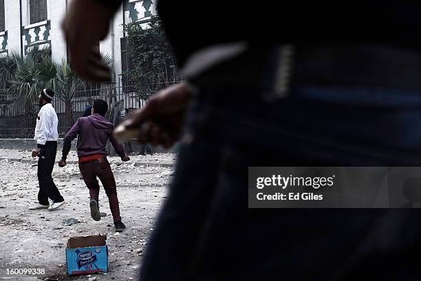 An Egyptian protester throws a rock toward Egyptian riot police during a protest following the announcement of the death penalty for 21 suspects in...