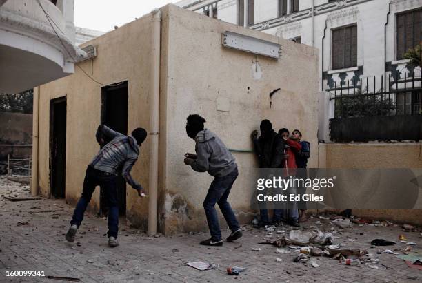 An Egyptian protester throws a rock toward Egyptian riot police during a protest following the announcement of the death penalty for 21 suspects in...
