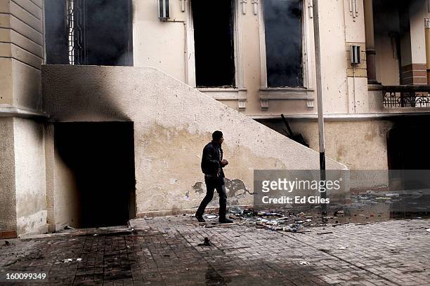 An Egyptian protester stands in front of a burning school building during a demonstration following the announcement of the death penalty for 21...