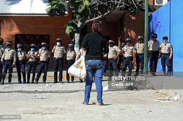 Police offciers stand guard as a relative of a deceased inmates waits outside of a morgue a day after a riot broke out at the Uribana prison in Lara...