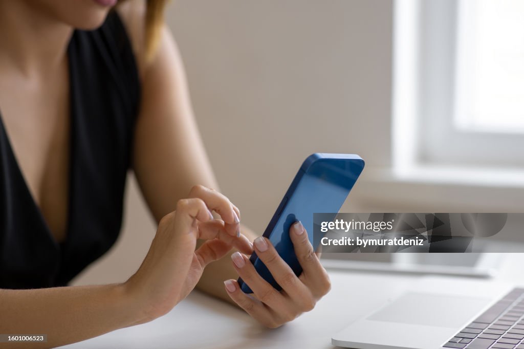 Manos de mujer usando un teléfono móvil