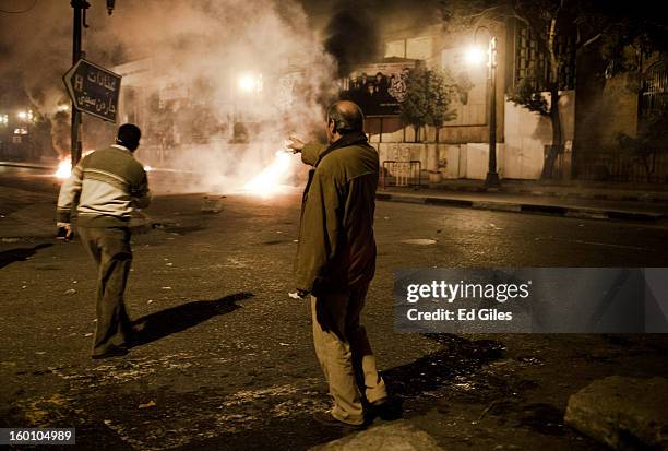 An Egyptian protester points toward approaching Egyptian riot police during a protest following the announcement of the death penalty for 21 suspects...