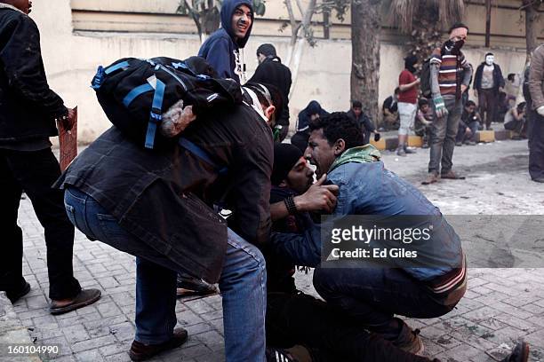 An Egyptian protester tries to carry an injured man away from clashes with Egyptian riot police during a protest following the announcement of the...