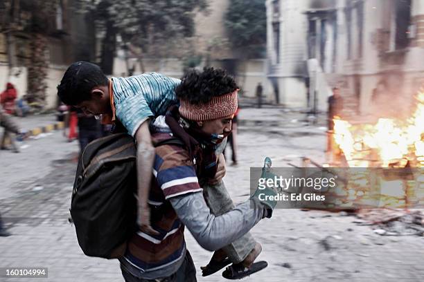 An Egyptian protester carries an injured boy away from clashes with Egyptian riot police during a protest following the announcement of the death...