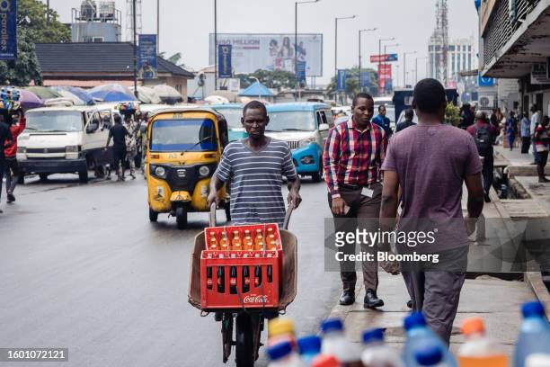 Worker transports crates of soda in a wheelbarrow along the marina road in the Central Business District of Lagos, Nigeria, on Monday, Aug. 14, 2023....