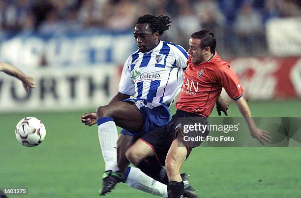 Kiki Musampa of Malaga is tackled by Sanchez Benito Alfredo of Osasuna during the Malaga v Osasuna Primera Liga match November 9, 2002 played at the...