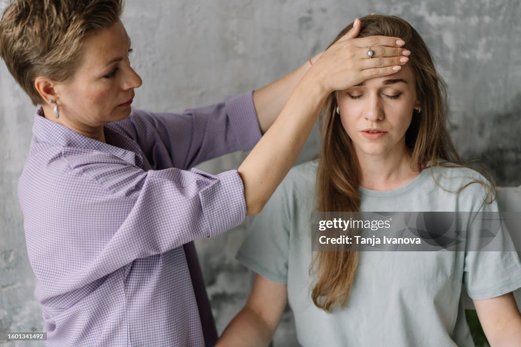 Therapist holding hand on the patient's head during hypnotherapy. Reiki therapy practice. Bioenergy healing expert practices. Alternative medicine, psychology, mental health concept.