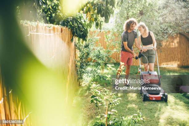 couple taking care of their lawn.  couple cutting the grass in the backyard. - garden talking photos et images de collection