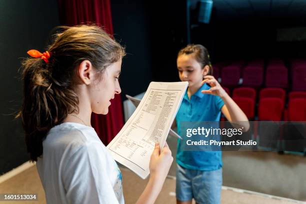 group of children enjoying drama club rehearsal. they are reading script with their drama teacher. - acteren stockfoto's en -beelden