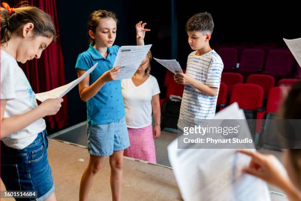 group of children enjoying drama club rehearsal. they are reading script with their drama teacher. - skolpjäs bildbanksfoton och bilder