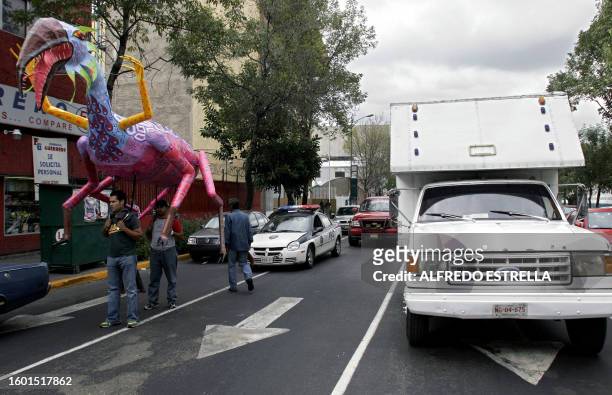 Assistants of Mexican craftswoman Elsa Linares carry an "alebrije" called "Head of Bird and Feet of Goat" in the streets of Mexico City before the...
