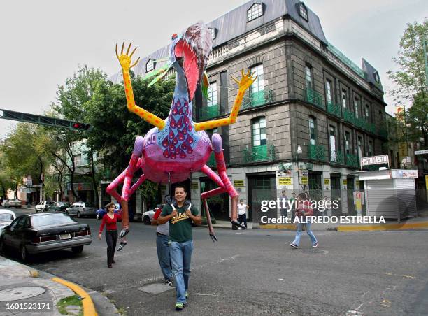 Assistans of Mexican craftswoman Elsa Linares carry an "alebrije" called "Head of Bird and Feet of Goat" in the streets of Mexico City before the...