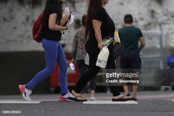 Shoppers carry milk and groceries after shopping in an Asda Group Ltd. Supermarket in Strood, UK, on Tuesday, Aug. 15, 2023. Grocery price inflation...