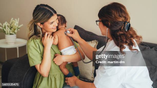 médico visitando a la madre joven en casa para el chequeo de rutina del recién nacido - comadrona fotografías e imágenes de stock