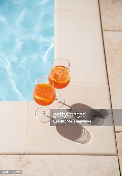 orange spritz glasses by the pool in warm sunlight in the summer - bassängkant bildbanksfoton och bilder
