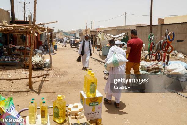 People walk past stalls at Sudan's some 350 kilometres north of Sudanese capital Khartoum on August 15, 2023. Darfur and the capital Khartoum have...