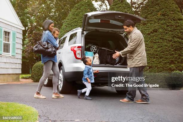 girl running towards father with mother carrying baby boy by car - middle class female stock pictures, royalty-free photos & images