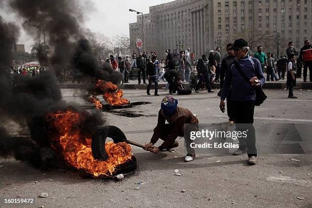 An Egyptian protester places a tire on a fire during a demonstration in Tahrir Square on January 27, 2013 in Cairo, Egypt. Violent protests continued...