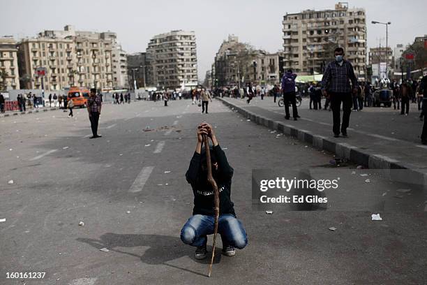 An Egyptian demonstrator squats down during a lull in fighting between protesters and riot police during a demonstration in Tahrir Square on January...