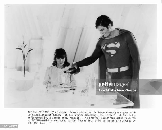 Margot Kidder watches as Christopher Reeve pours her a glass of champagne in a scene from the film 'Superman II', 1980.