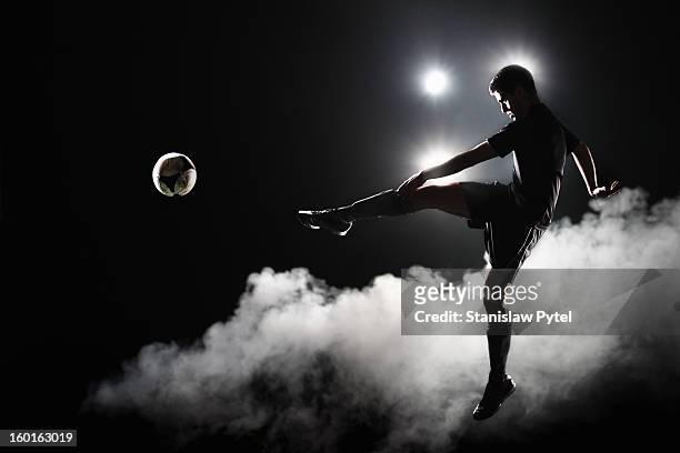 soccer player kicking the ball at night on stadium - futbolistas fotografías e imágenes de stock