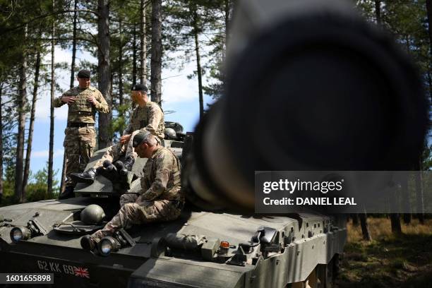 Member of the Queen's Royal Hussars and two members of Royal Tank Regiment sit on a tank as they take part in a training session of British forces...