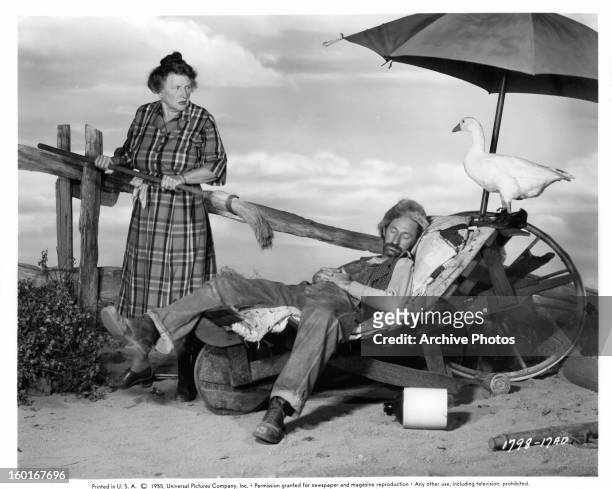 Marjorie Main holds a broom up to a sleeping Arthur Hunnicutt in a scene from the film 'The Kettles In The Ozarks', 1956.