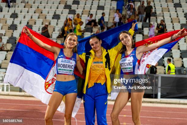 Oleksandra Chernukha of Ukraine, Teodora Boberic of Serbia and Aleksandrija Mitrovic of Serbia pose with flags after Women's Triple Jump during...