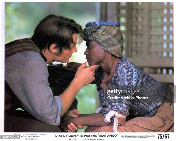 Perry King leaning in to kiss Brenda Sykes in a scene from the film 'Mandingo', 1975.