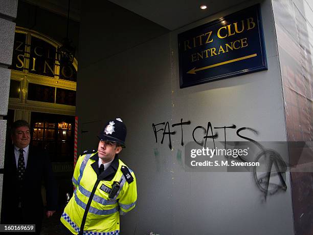 The words 'Fat Cats' with an anarchy symbol are spray painted outside one of London's most luxurious hotel, The Ritz in Mayfair. A policeman peers...