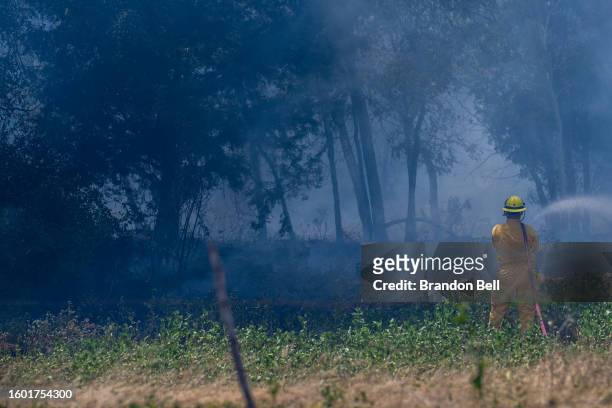 Firefighter works to put out a wildfire during an excessive heat warning on August 08, 2023 in Hays County, Texas. The city of Austin and its...