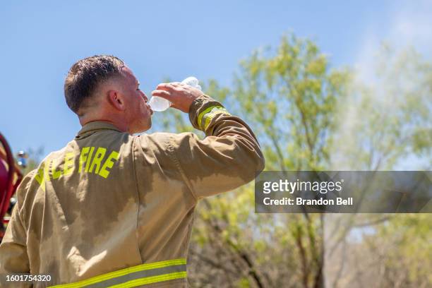 Firefighter takes a water break while combatting a wildfire during an excessive heat warning on August 08, 2023 in Hays County, Texas. The city of...